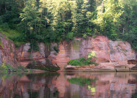 beautiful day on the river, sandstone cliffs and tree reflections in the water, blue sky reflected in the river water, Gauja river, Latviaの写真素材