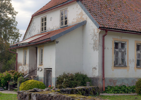 old white building with a red roof, surrounded by trees and shrubs in autumn colors, autumn timeの写真素材