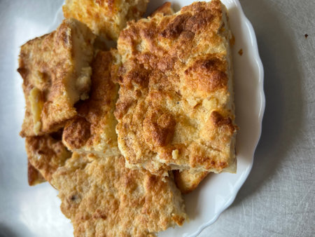 Close up of a plate of fried bread on white tablecloth.