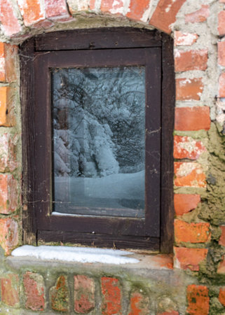 brick basement wall, window reflecting the winter view, old window in vintage style