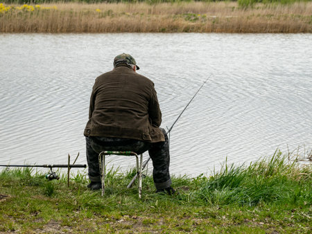 spring landscape with a fisherman on the shore of the lake, fishing accessories in the green hall...