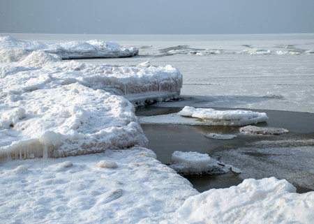winter landscape by the sea, snowy, interesting ice shapes on the sea shore, dunes covered with a...