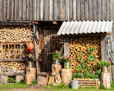 firewood pile decorated with flowers and garden objects, firewood stock for winter, garden...