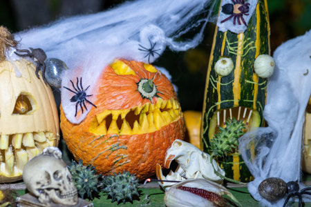 Unusual original Halloween composition, scary Jack O Lantern Halloween pumpkins in the dark, carved pumpkins with different faces surrounded by different Halloween decorationsの写真素材