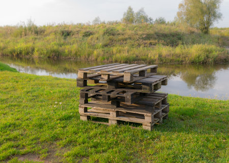 autumn landscape on the shore of the lake, wooden pallets standing in the middle of the meadow, autumn colors in natureの写真素材