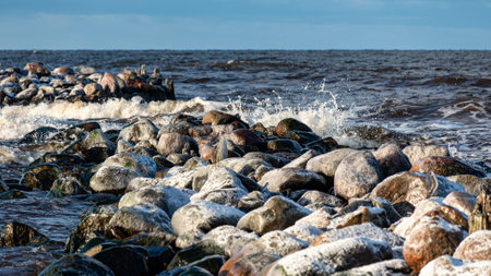 winter landscape with the seashore, windy winter day, water splashes, stone pier on the seashore, Baltic Sea, Latviaの写真素材