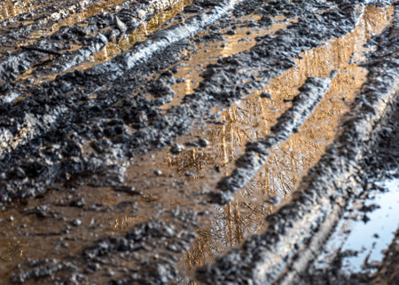 landscape with a muddy, wet road, mud texture, snow remnants, winter roadの写真素材
