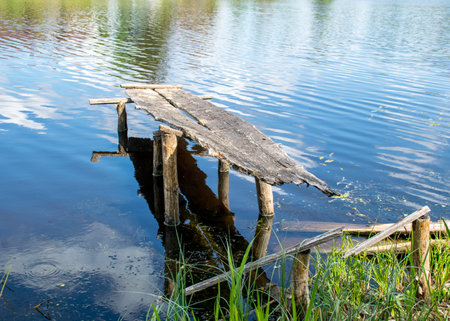 summer landscape with an old wooden footbridge in a small forest lakeの写真素材