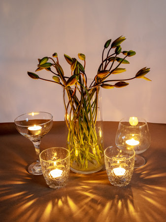picture with yellow tulips in a vase by candlelight, interesting reflections and shadowsの写真素材