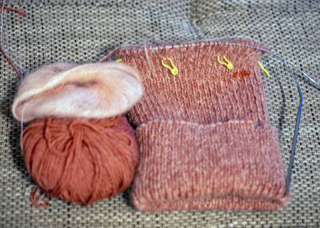 unfinished knitting, cozy, homely atmosphere, women's hobby knitting, yarn in warm colors, close-up...