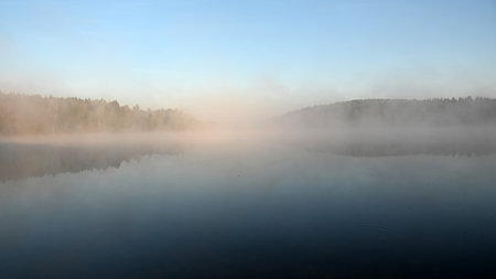 early autumn morning by the lake, fog hides the outlines of trees and bushes, blurred background, Latviaの写真素材