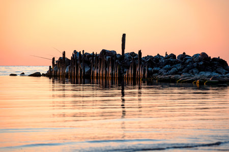 Magical sunset by the sea, old stone pier, the last rays of the sun reflected in the calm sea...