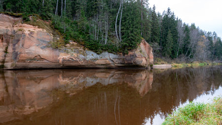beautiful view of sandstone outcrops on the riverbank, autumn landscape, reflections in the river, Gauja, Erglu cliffs, Latviaの写真素材