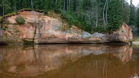 beautiful view of sandstone outcrops on the riverbank, autumn landscape, reflections in the river, Gauja, Erglu cliffs, Latviaの写真素材