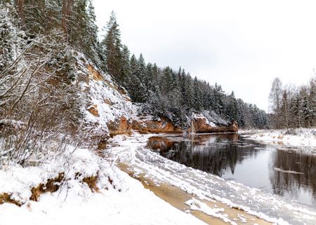 winter landscape with river and sandstone outcrops, river frozen with ice, snow fallen on trees, Erglu cliffs, Cesis municipality, Latviaの写真素材