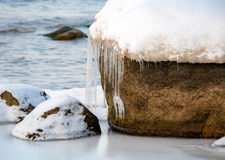 colorful winter landscape by the sea, frozen stones with icicles on the seashore, sunset colors, snow and ice, Rocky coast of Vidzeme, Latviaの写真素材