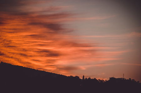Some intense red and orange clouds reach the shadows of the gound while sunset arrivesの写真素材