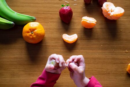 Baby s hand manipulating different fruits on a wooden tableの写真素材