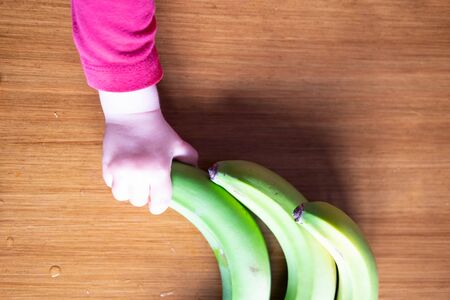Baby s hand manipulating different fruits on a wooden tableの写真素材