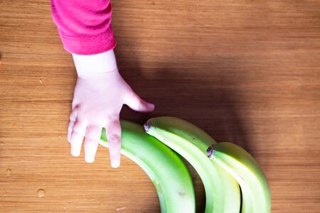 Baby s hand manipulating different fruits on a wooden tableの写真素材