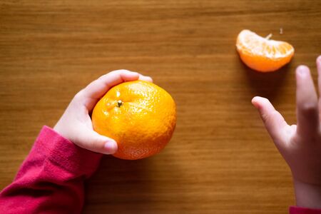 Baby s hand manipulating different fruits on a wooden tableの写真素材