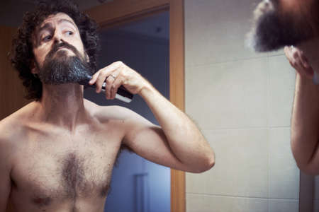 Middle-aged hispanic man cutting his beardの写真素材