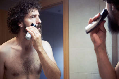 Middle-aged hispanic man cutting his beardの写真素材