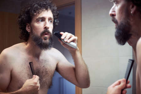 Middle-aged hispanic man cutting his beardの写真素材