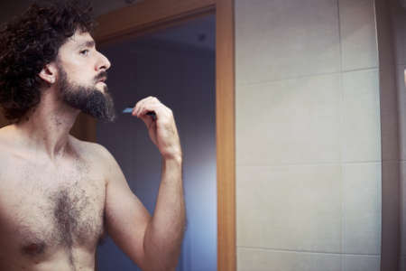 Middle-aged hispanic man cutting his beardの写真素材