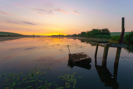 old fishing pier by the lake during sunriseの写真素材