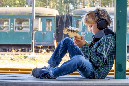 kid playing guitar at old railroad station