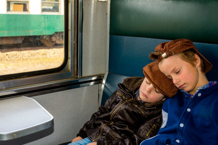 two boys sleeping in a train during their travelの写真素材