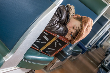 kid fell asleep on his suitcase in a trainの写真素材