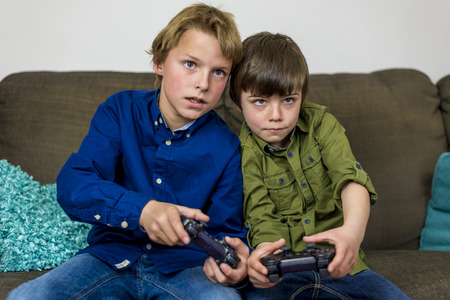 two little brothers on a couch,playing a computer gameの写真素材