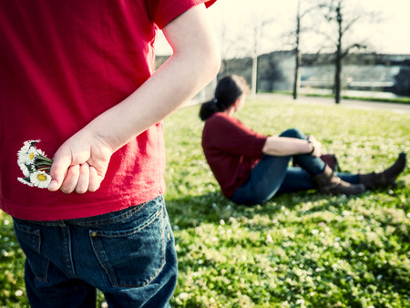 boy holding daisies behind his back, walking towards his mother, vintage filter addedの写真素材