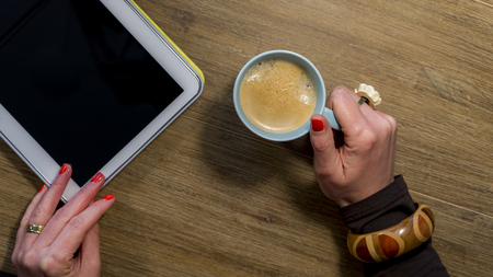 womans hands with nail polish holding coffee and tabletの写真素材