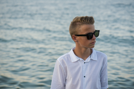wealthy looking kid on a holiday location with the sea behind him.の写真素材