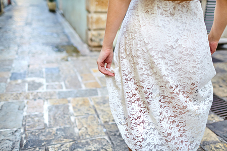 Female hand and white dress. A girl walks along the narrow streets of the old cityの写真素材