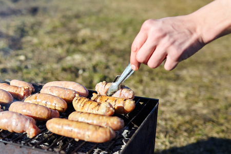 Raw sausages from chicken meat are cooked on the grill. Concept of eating outdoor during summer timeの写真素材