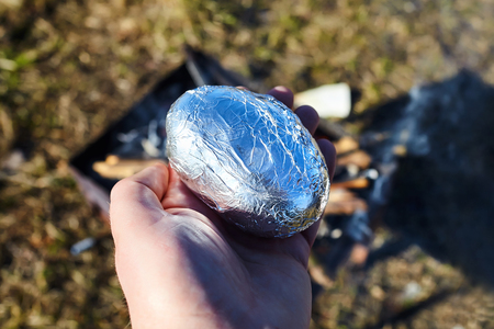 potatoes in foil in male handの写真素材