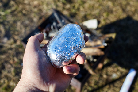 potatoes in foil in male handの写真素材