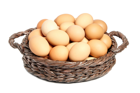 Beige chicken eggs in a brown wicker basket の写真素材