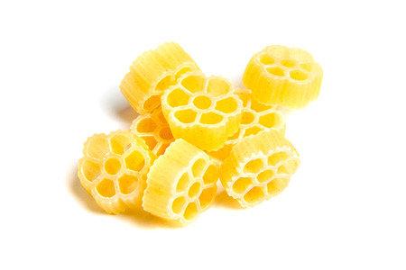 Raw uncooked Rotelle dry italian pasta. Ruote, wagon wheel shaped. Heap, isolated on white backgroundの写真素材