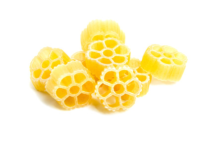 Raw uncooked Rotelle dry italian pasta. Ruote, wagon wheel shaped. Heap, isolated on white backgroundの写真素材