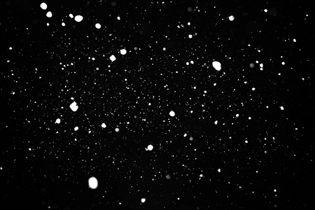 Snowfall, shot of  white flying snowflakes in the air. Snowstorm texture on a black background. Bokeh lightsの写真素材