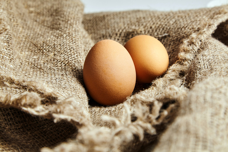Two brown and speckled fresh chicken eggs in on sackcloth texture background . Closeupの写真素材