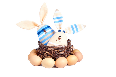 Two soft toy of a striped smiling rabbits, sitting in a basket of birch branches.の写真素材