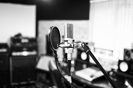 Silver condenser microphone with pop filter and anti-vibration mount. Music studio. Professional sound and voice recording instrument. Side view. Selective focus. Blurred background. Black and whiteの写真素材