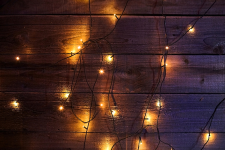 Bright glowing Christmas garland on a wooden background. New Year's lights. Festive Decoration. Yellow blue toningの写真素材