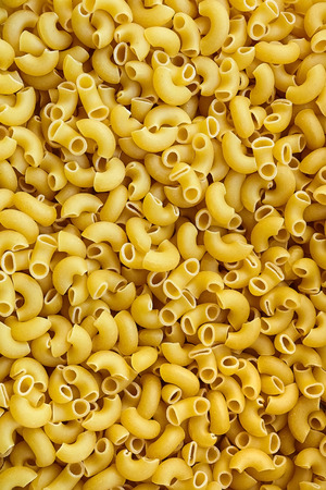 Uncooked italian pasta background. Elbow Macaroni with a smooth surfaceの写真素材